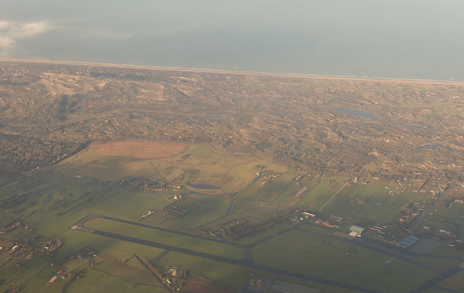 Luchtfoto van het voormalige vliegkamp Valkenburg met Katwijk en de zee erachter